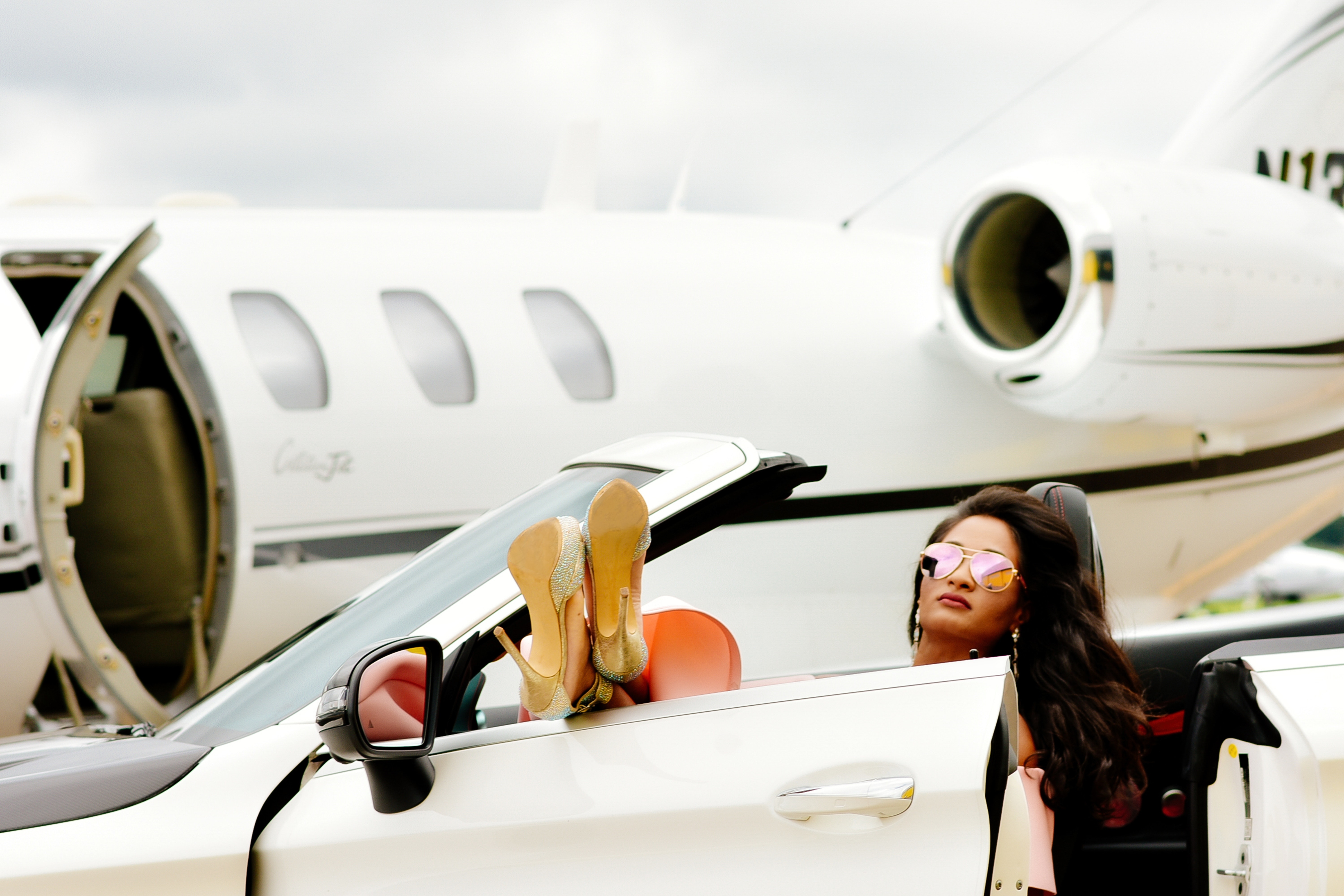 donna su macchina di lusso davanti aereo privato