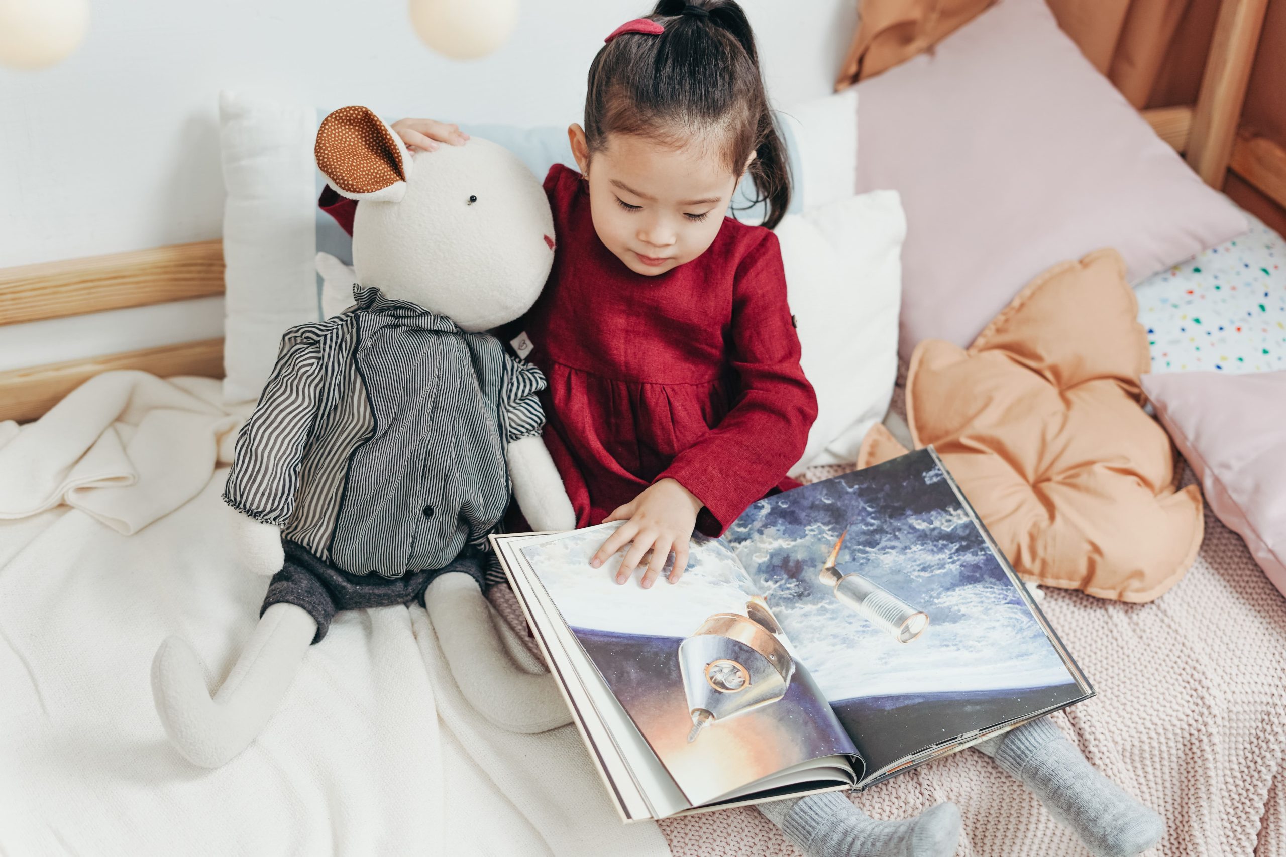 bambina che legge un libro con peluche